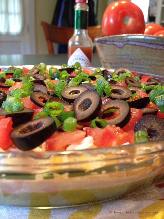 San Francisco Layer Dip: zippy guacamole dip with greek yogurt, taco seasoning, cheese, tomatoes, olives, green onions and hot pepper sauce.