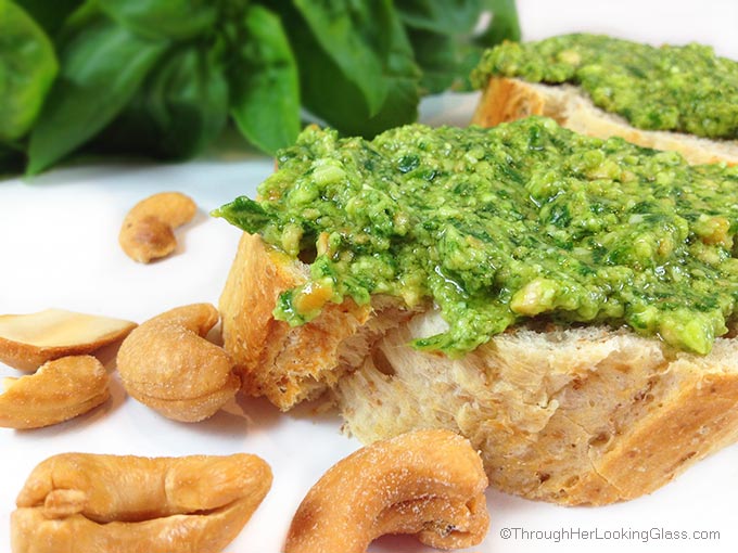 this easy cashew basil pesto spread on a piece of bread with roasted cashews in the foreground