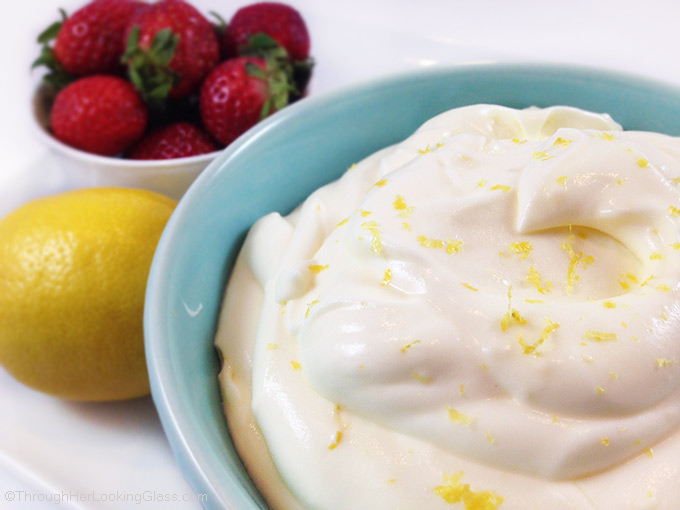 Lemon cream with lemon curd and strawberries in a small blue bowl garnished with lemon zest