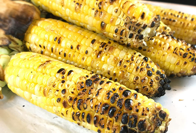 This Charred Mexican Street Corn Recipe is so easy! Grilled corn on the cob w/crumbled cotija, sprinkled w/chili powder, spritzed with lime. Heavenly!