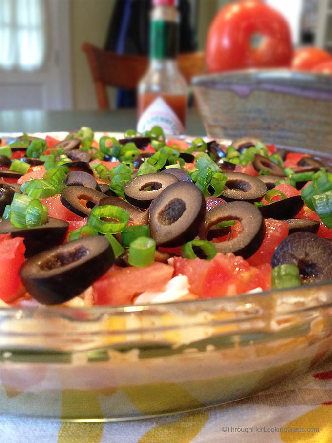 San Francisco Layer Dip: zippy guacamole dip with greek yogurt, taco seasoning, cheese, tomatoes, olives, green onions and hot pepper sauce.