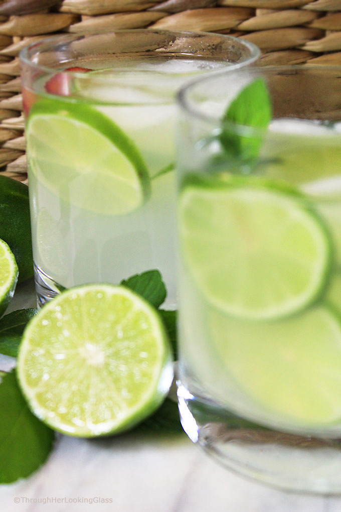 Two glasses of this old-fashioned limeade in glasses with ice, lime slices, and fresh mint
