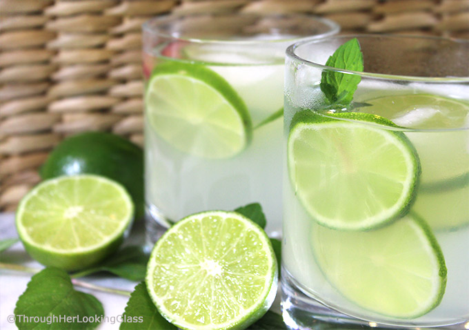 Two glasses of this old-fashioned limeade in glasses with ice, lime slices, and fresh mint